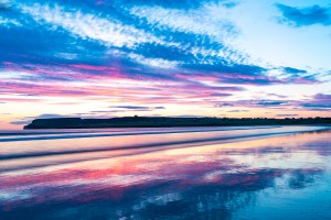 Photo of sunset reflections on the wet surface of Dunnet Beach.