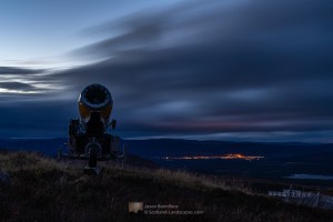 Photo of a Cairngorm Mountain ski centre snow cannon in place ready for winter. I came across this one with the bright lights of Aviemore behind during descent at dusk.